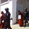 monks with placards around their necks are lead away from their monastery